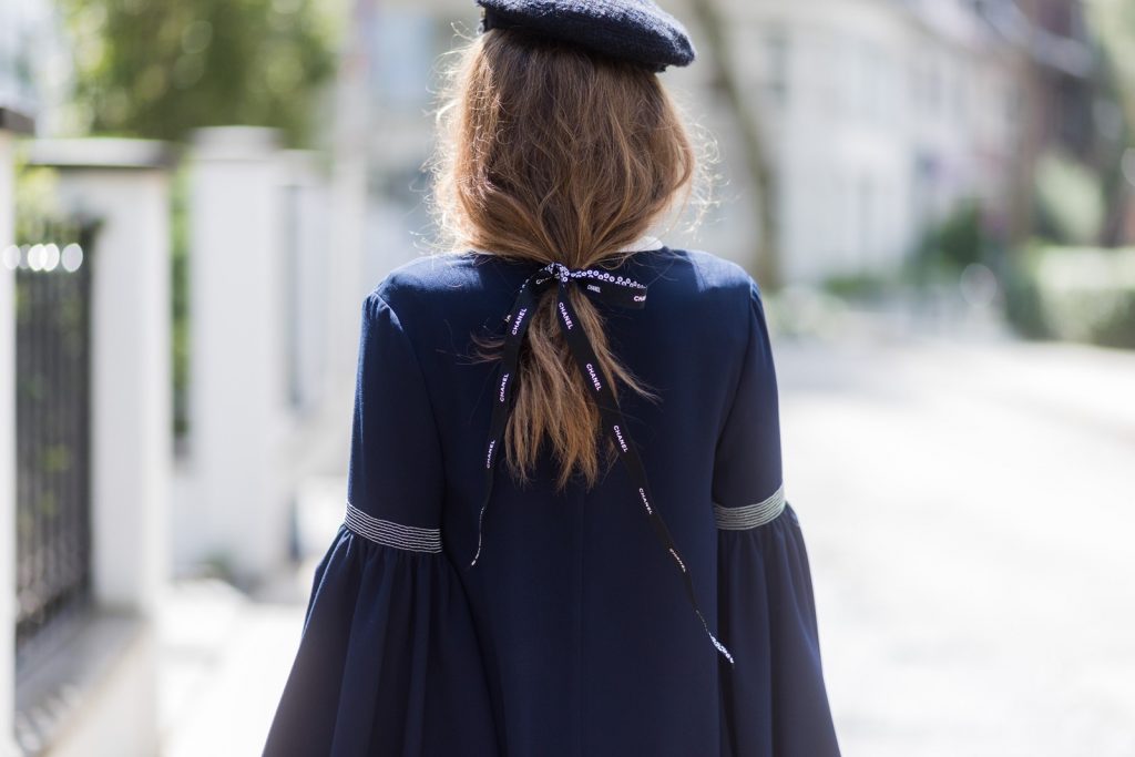 Model and fashion blogger Alexandra Lapp wearing a navy dress with oversized sleeves and a white tie-neck blouse from Steffen Schraut, Chanel tweed cap, baroque Fendi sock-boots in black and white, Chanel 2.55 classic back in white leather with black pearls on August 4, 2017 in Duesseldorf, Germany. 
