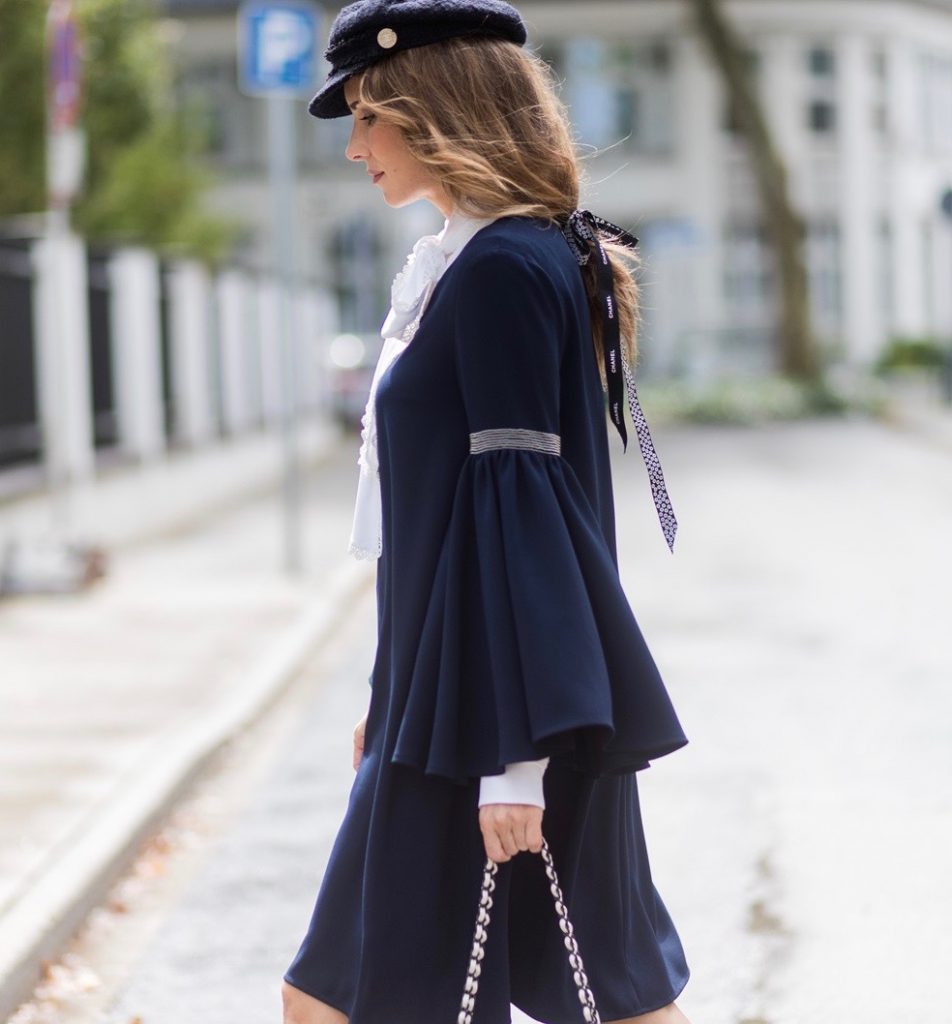 Model and fashion blogger Alexandra Lapp wearing a navy dress with oversized sleeves and a white tie-neck blouse from Steffen Schraut, Chanel tweed cap, baroque Fendi sock-boots in black and white, Chanel 2.55 classic back in white leather with black pearls on August 4, 2017 in Duesseldorf, Germany. 