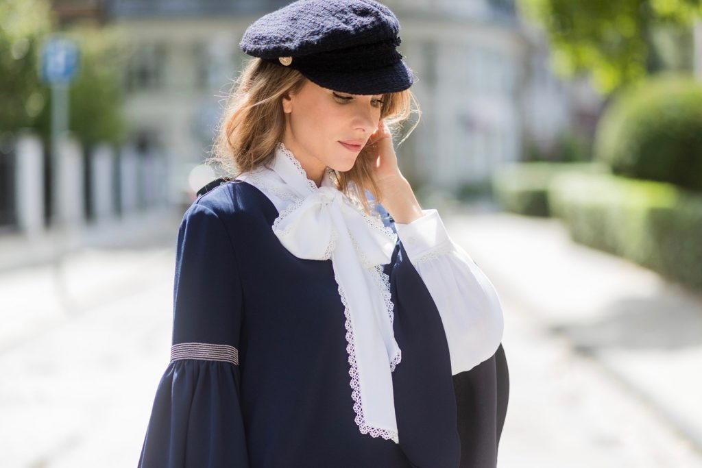 Model and fashion blogger Alexandra Lapp wearing a navy dress with oversized sleeves and a white tie-neck blouse from Steffen Schraut, Chanel tweed cap, baroque Fendi sock-boots in black and white, Chanel 2.55 classic back in white leather with black pearls on August 4, 2017 in Duesseldorf, Germany. 