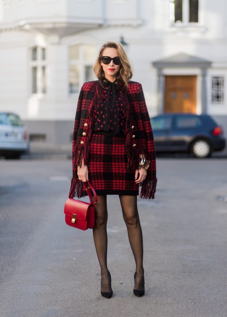 Model and fashion blogger Alexandra Lapp wearing a military jacket in red and black with checkered pattern and frayed sleeves from Balmain, plaid pattern high waist mini skirt by Balmain, red heart intarsia knit by Red Valentino, Celine Box bag in red and red lacquer pumps by Gianvito Rossi, rose gold ring with baguette diamonds on August 4, 2017 in Duesseldorf, Germany.
