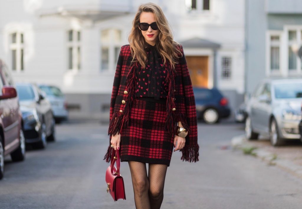 Model and fashion blogger Alexandra Lapp wearing a military jacket in red and black with checkered pattern and frayed sleeves from Balmain, plaid pattern high waist mini skirt by Balmain, red heart intarsia knit by Red Valentino, Celine Box bag in red and red lacquer pumps by Gianvito Rossi, rose gold ring with baguette diamonds on August 4, 2017 in Duesseldorf, Germany.