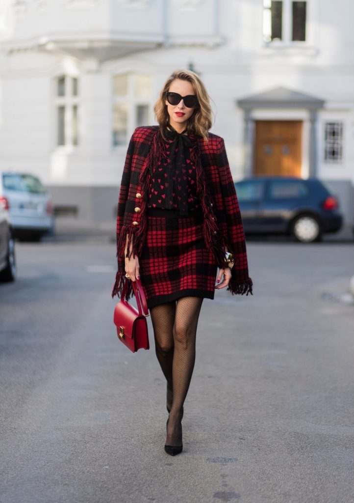 Model and fashion blogger Alexandra Lapp wearing a military jacket in red and black with checkered pattern and frayed sleeves from Balmain, plaid pattern high waist mini skirt by Balmain, red heart intarsia knit by Red Valentino, Celine Box bag in red and red lacquer pumps by Gianvito Rossi, rose gold ring with baguette diamonds on August 4, 2017 in Duesseldorf, Germany.