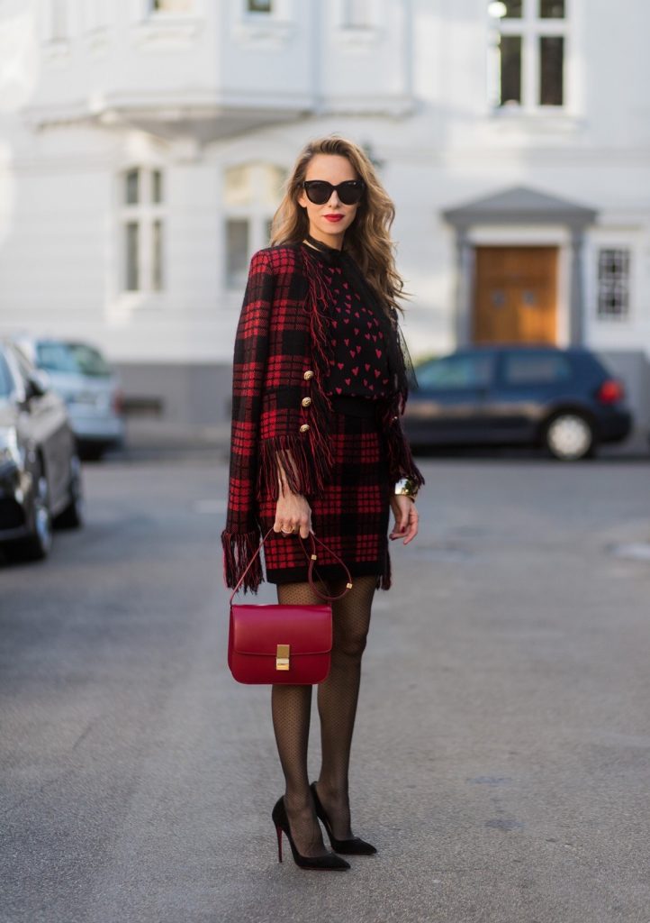Model and fashion blogger Alexandra Lapp wearing a military jacket in red and black with checkered pattern and frayed sleeves from Balmain, plaid pattern high waist mini skirt by Balmain, red heart intarsia knit by Red Valentino, Celine Box bag in red and red lacquer pumps by Gianvito Rossi, rose gold ring with baguette diamonds on August 4, 2017 in Duesseldorf, Germany.
