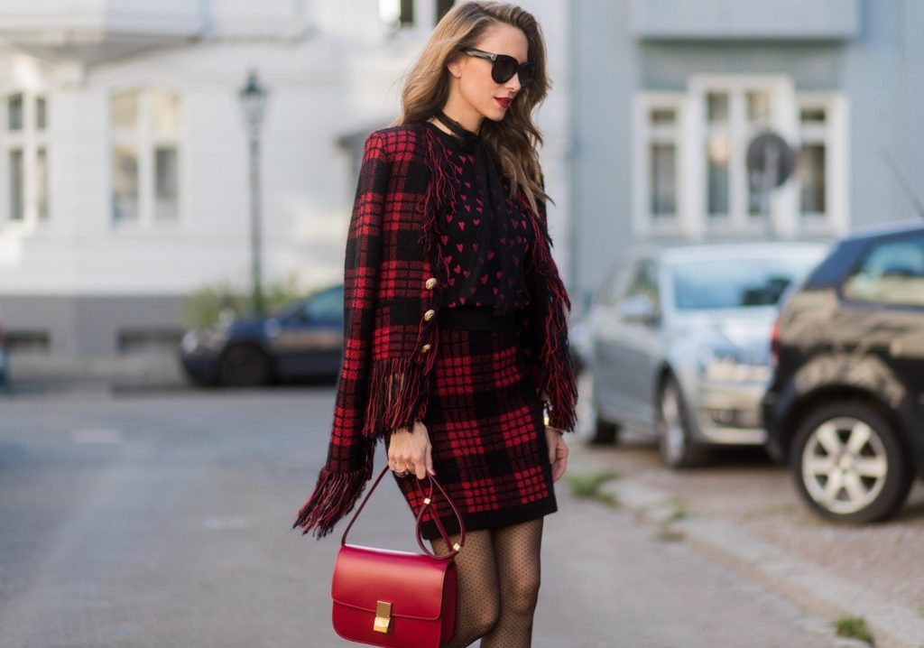 Model and fashion blogger Alexandra Lapp wearing a military jacket in red and black with checkered pattern and frayed sleeves from Balmain, plaid pattern high waist mini skirt by Balmain, red heart intarsia knit by Red Valentino, Celine Box bag in red and red lacquer pumps by Gianvito Rossi, rose gold ring with baguette diamonds on August 4, 2017 in Duesseldorf, Germany.
