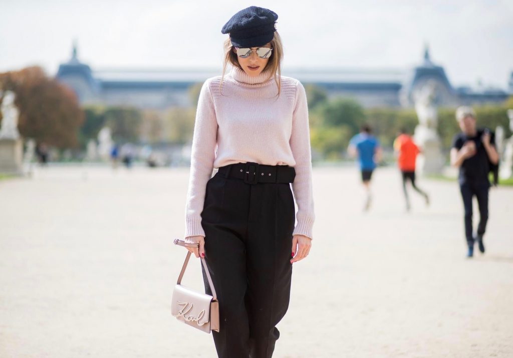 Alexandra Lapp wearing high waist pants in black from Zara, cashmere turtleneck in light pink from Jil Sander, light pink calf leather logo plaque shoulder bag from Karl Lagerfeld, Karl Lagerfeld bag, mirrored sunglasses by Le Specs, hat by Chanel, IWC Portugieser watch and Christian Louboutin Feerica heels with crystal embellished flower and glitter is seen during Paris Fashion Week Spring/Summer 2018 on September 29, 2017 in Paris, France.