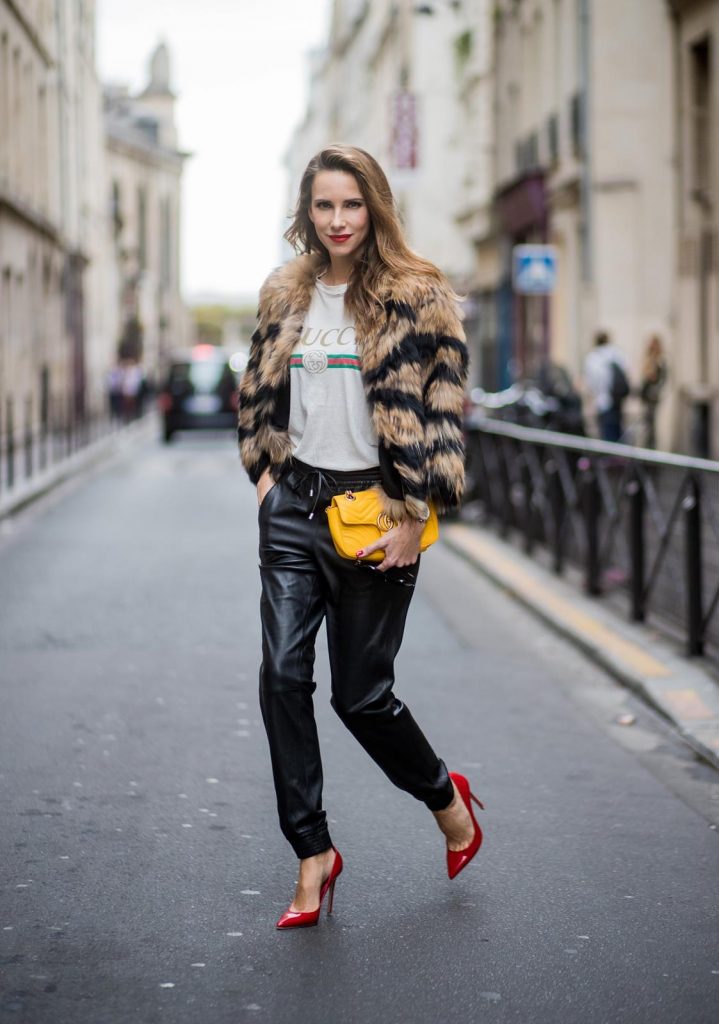 Alexandra Lapp wearing leather trackies in black from Set Fashion, vintage style Gucci logo tee, little fur jacket by Set, yellow GG Marmont matelasse shoulder bag by Gucci, red lacquer heels from Gianvito Rossi and Audrey sunglasses from Celine is seen during Paris Fashion Week Spring/Summer 2018 on September 27, 2017 in Paris, France.
