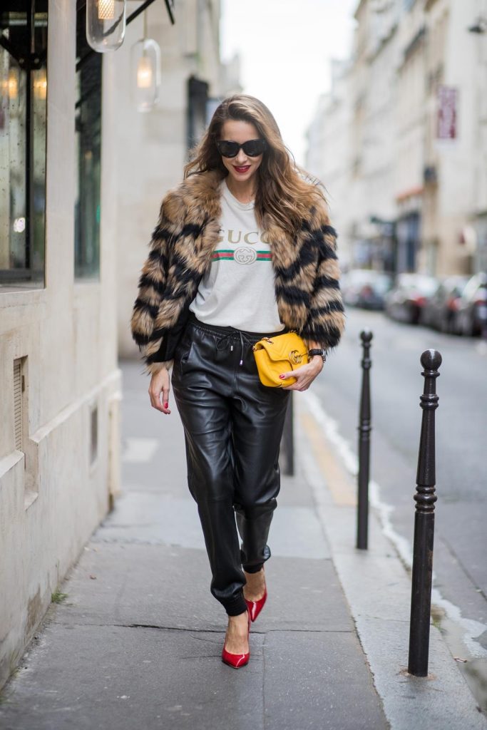 Alexandra Lapp wearing leather trackies in black from Set Fashion, vintage style Gucci logo tee, little fur jacket by Set, yellow GG Marmont matelasse shoulder bag by Gucci, red lacquer heels from Gianvito Rossi and Audrey sunglasses from Celine is seen during Paris Fashion Week Spring/Summer 2018 on September 27, 2017 in Paris, France.