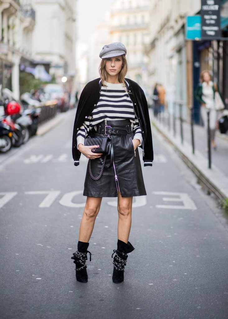 Alexandra Lapp wearing French Chic, an A-line leather rocky biker skirt from SET Fashion, striped knit jumper from Zara, plaid Zara hat, Isabel Marant slouchy boots, detailed with chain-trimmed ties to wrap around the leg, black Boy bag from Chanel and velvet bomber jacked with a Cosmo application is seen during Paris Fashion Week Spring/Summer 2018 on September 29, 2017 in Paris, France.