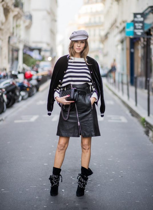 Alexandra Lapp wearing French Chic, an A-line leather rocky biker skirt from SET Fashion, striped knit jumper from Zara, plaid Zara hat, Isabel Marant slouchy boots, detailed with chain-trimmed ties to wrap around the leg, black Boy bag from Chanel and velvet bomber jacked with a Cosmo application is seen during Paris Fashion Week Spring/Summer 2018 on September 29, 2017 in Paris, France.