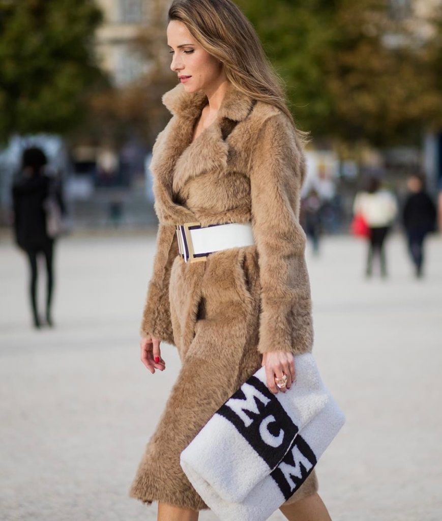 Alexandra Lapp wearing Morganite jewelry, rings and earrings by Schubart an oversized MCM Stark Pouch in Shearling Stripe, a lambskin coat in light brown by Yves Salomon, black and white big waist-belt from Balmain and striped Christian Louboutin 'So Kate' heels is seen during Paris Fashion Week Spring/Summer 2018 on September 28, 2017 in Paris, France.