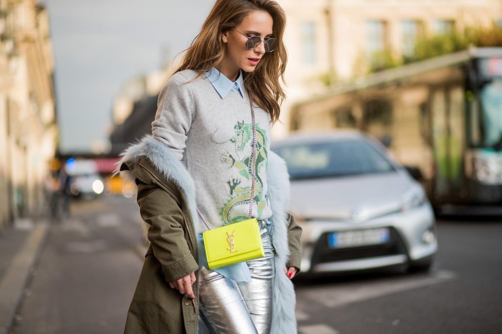 silver pants, Balmain, Heartbreaker, Yves Salomon, Equipment, Saint Laurent, YSL, Christian Louboutin, Le Specs Alexandra Lapp wearing silver pants in leather and biker style by Balmain, long blue silk blouse from Equipment, cashmere pullover in grey with a green dragon application by Heartbreaker, green parka equipped with light blue fur inside, silver mirrored sunglasses by le Specs, Christian Louboutin So Kate heels in neon yellow and the Kate Monogram Chain Grain leather shoulder bag in neon yellow by Saint Laurent is seen during Paris Fashion Week Spring/Summer 2018