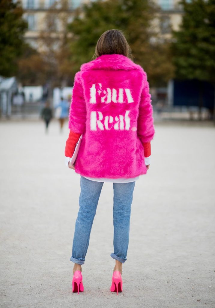 Alexandra Lapp wearing a fake fur jacket in pink from Jakke with a Faux Real statement on the back, red cashmere jumper by Heartbreaker with golden buttons, a long white blouse by Celine, Levis ReDone denim, Christian Louboutin heels in neon pink, sunglasses by Le Specs and a clutch by Yazburkey with a Dazzlin Smile application is seen during Paris Fashion Week Spring/Summer 2018 on September 27, 2017 in Paris, France.