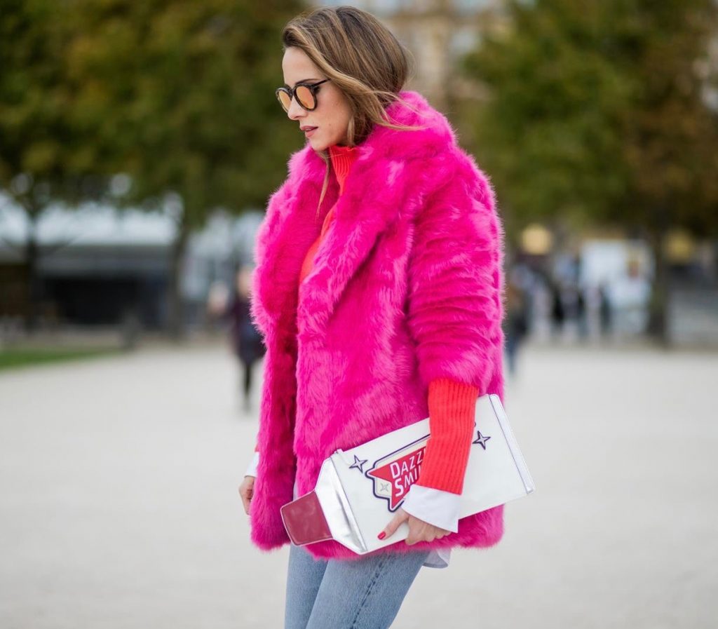 Alexandra Lapp wearing a fake fur jacket in pink from Jakke with a Faux Real statement on the back, red cashmere jumper by Heartbreaker with golden buttons, a long white blouse by Celine, Levis ReDone denim, Christian Louboutin heels in neon pink, sunglasses by Le Specs and a clutch by Yazburkey with a Dazzlin Smile application is seen during Paris Fashion Week Spring/Summer 2018 on September 27, 2017 in Paris, France.