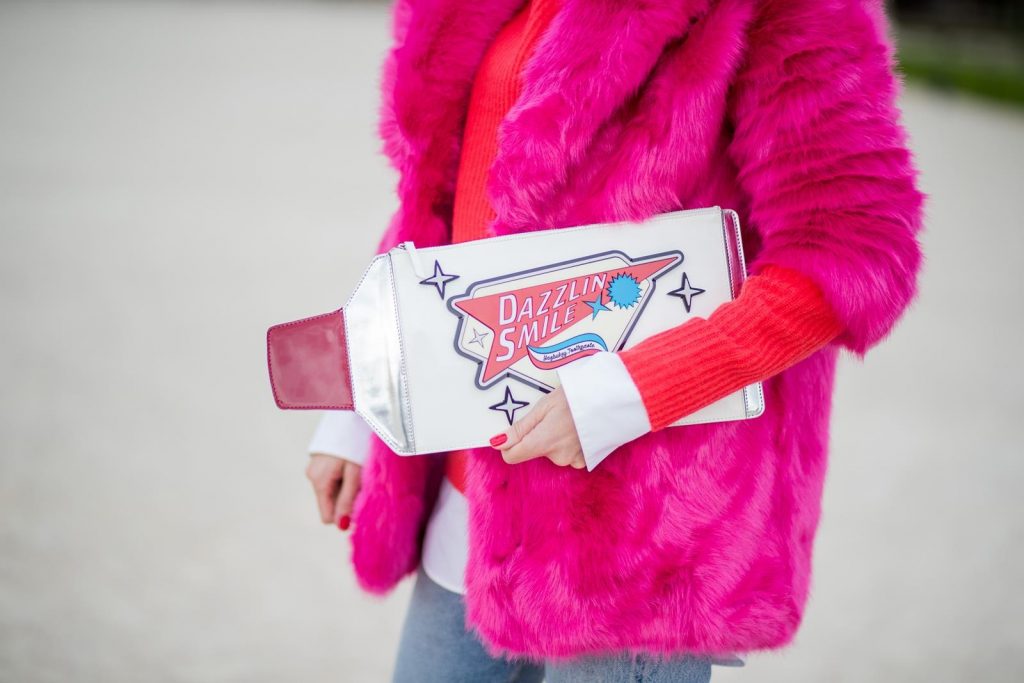 Alexandra Lapp wearing a fake fur jacket in pink from Jakke with a Faux Real statement on the back, red cashmere jumper by Heartbreaker with golden buttons, a long white blouse by Celine, Levis ReDone denim, Christian Louboutin heels in neon pink, sunglasses by Le Specs and a clutch by Yazburkey with a Dazzlin Smile application is seen during Paris Fashion Week Spring/Summer 2018 on September 27, 2017 in Paris, France.