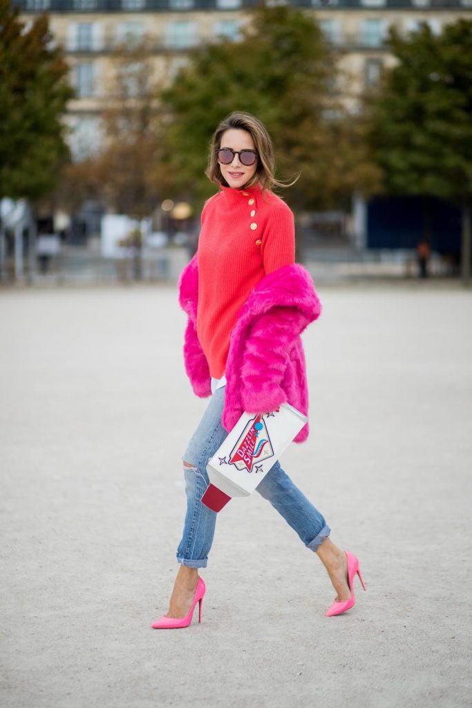 Alexandra Lapp wearing a fake fur jacket in pink from Jakke with a Faux Real statement on the back, red cashmere jumper by Heartbreaker with golden buttons, a long white blouse by Celine, Levis ReDone denim, Christian Louboutin heels in neon pink, sunglasses by Le Specs and a clutch by Yazburkey with a Dazzlin Smile application is seen during Paris Fashion Week Spring/Summer 2018 on September 27, 2017 in Paris, France.