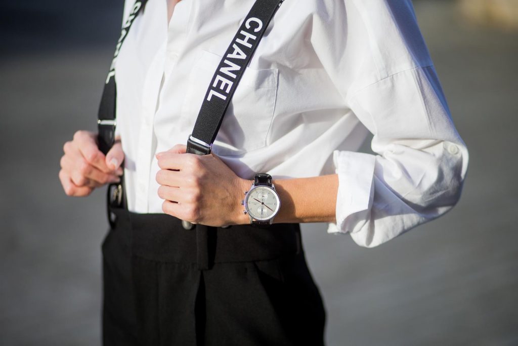 Alexandra Lapp wearing black and white vintage Chanel suspenders with Chanel logo in black and white, a white oversized shirt from Steffen Schraut, black high waist pants from Zara, XL backpack in lambskin with black and white MCM logo and Chanel baker boy cap in black tweed and ballerinas in white with black tip and logo from Chanel on November 27, 2017 in Barcelona, Spain.