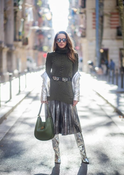 Alexandra Lapp wearing metallic look, a pleated skirt in a washed out silver metallic and black style, long knitted dark green Celine turtle neck pullover with cable stitch, black waist belt from Hermes with heavy silver buckle and silver stud details, short cut silver leather jacket with zippers from Set Fashion, silver metallic boots from H&M, large green Patricia Hobo bag from MCM and sunglasses from Le Specs on November 28, 2017 in Barcelona, Spain.