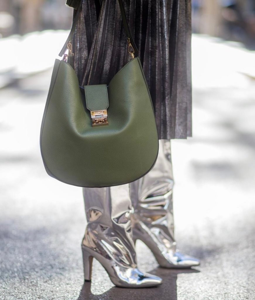 Alexandra Lapp wearing metallic look, a pleated skirt in a washed out silver metallic and black style, long knitted dark green Celine turtle neck pullover with cable stitch, black waist belt from Hermes with heavy silver buckle and silver stud details, short cut silver leather jacket with zippers from Set Fashion, silver metallic boots from H&M, large green Patricia Hobo bag from MCM and sunglasses from Le Specs on November 28, 2017 in Barcelona, Spain.
