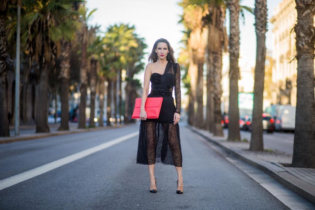 Alexandra Lapp wearing a little black dress, asymmetric shoulder dress with a delicate floral lace and a velvet fitted bustier from Three Floor, Pigalle Christian Louboutin black patent leather heels and a simple MCM pouch in marigold orange on November 29, 2017 in Barcelona, Spain.