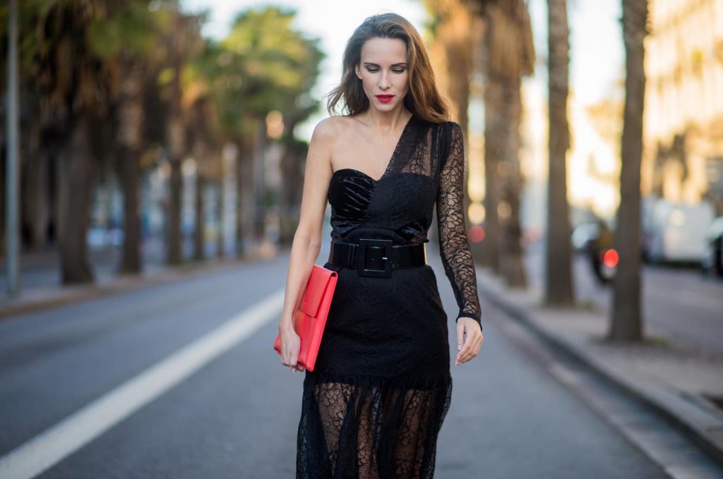 Alexandra Lapp wearing a little black dress, asymmetric shoulder dress with a delicate floral lace and a velvet fitted bustier from Three Floor, Pigalle Christian Louboutin black patent leather heels and a simple MCM pouch in marigold orange on November 29, 2017 in Barcelona, Spain.