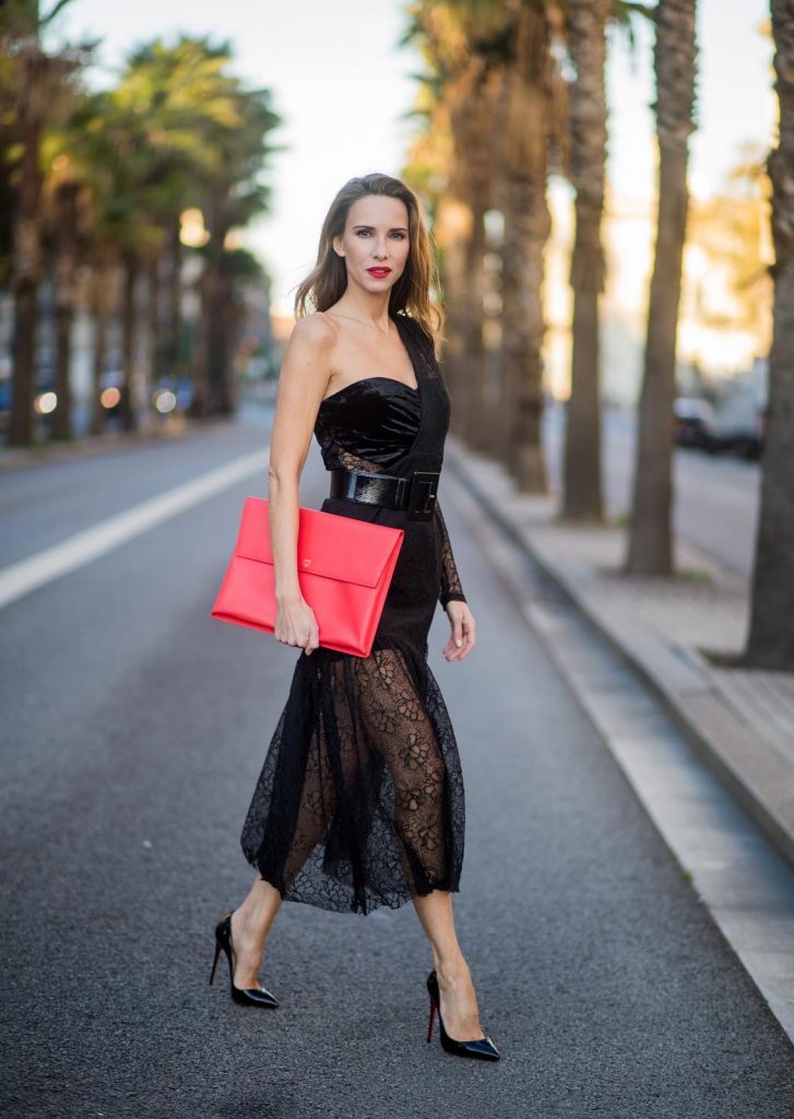 Alexandra Lapp wearing a little black dress, asymmetric shoulder dress with a delicate floral lace and a velvet fitted bustier from Three Floor, Pigalle Christian Louboutin black patent leather heels and a simple MCM pouch in marigold orange on November 29, 2017 in Barcelona, Spain.