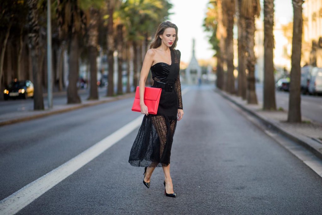Alexandra Lapp wearing a little black dress, asymmetric shoulder dress with a delicate floral lace and a velvet fitted bustier from Three Floor, Pigalle Christian Louboutin black patent leather heels and a simple MCM pouch in marigold orange on November 29, 2017 in Barcelona, Spain.