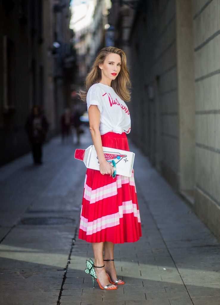 Let us swing - Alexandra Lapp wearing a pleated skirt from Valentino, white t-shirt from Valentino with label print written over the chest with red lipstick, high heel sandals from Sophia Webstar with butterflies on the back, handbag in shape of toothpaste from Yazbukey on November 27, 2017 in Barcelona, Spain.