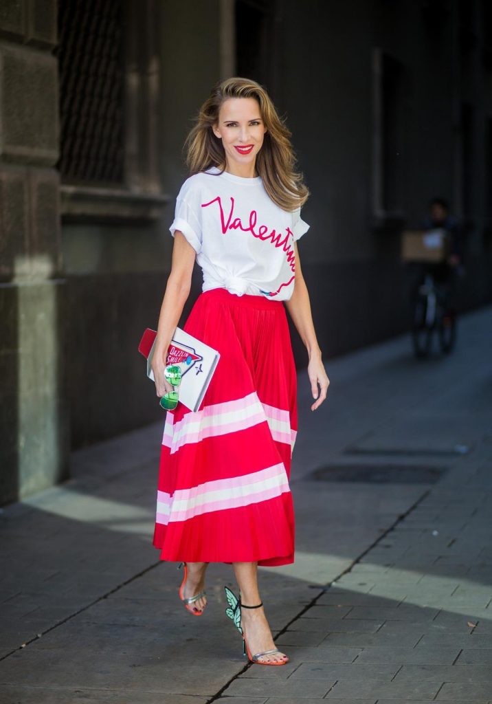 Let us swing - Alexandra Lapp wearing a pleated skirt from Valentino, white t-shirt from Valentino with label print written over the chest with red lipstick, high heel sandals from Sophia Webstar with butterflies on the back, handbag in shape of toothpaste from Yazbukey on November 27, 2017 in Barcelona, Spain.