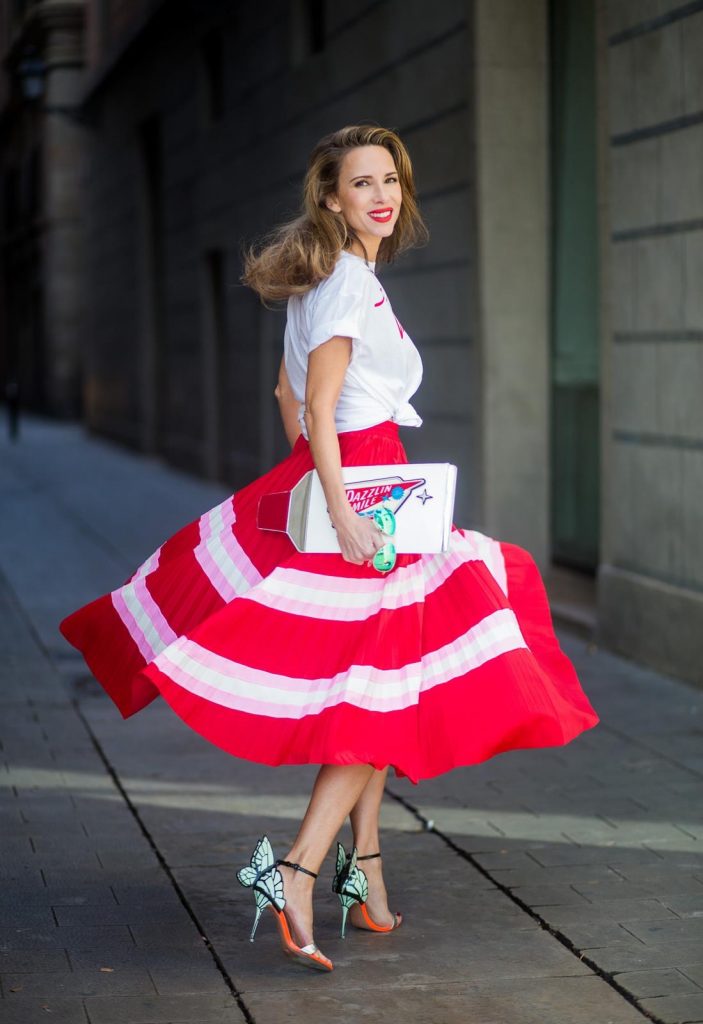 Let us swing - Alexandra Lapp wearing a pleated skirt from Valentino, white t-shirt from Valentino with label print written over the chest with red lipstick, high heel sandals from Sophia Webstar with butterflies on the back, handbag in shape of toothpaste from Yazbukey on November 27, 2017 in Barcelona, Spain.
