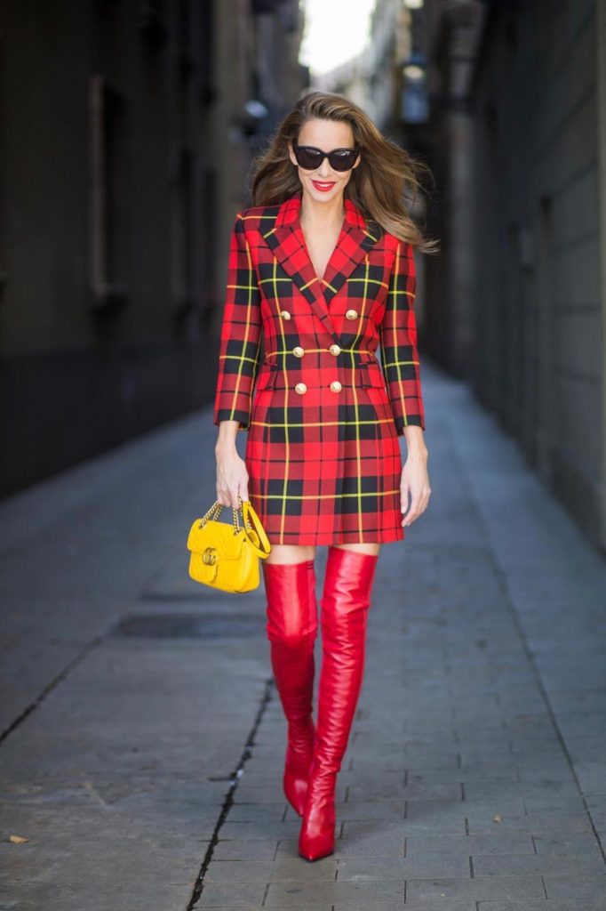 Alexandra Lapp wearing a look all about red, a red checked plaid wool blazer-dress with golden buttons by Balmain, ribbed knit Fendi thigh boots in red Rockoko leather, a yellow Marmont matelasse shoulder bag by Gucci and black Audrey sunglasses by Celine on November 27, 2017 in Barcelona, Spain.