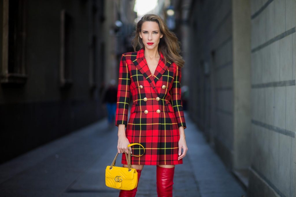 Alexandra Lapp wearing a look all about red, a red checked plaid wool blazer-dress with golden buttons by Balmain, ribbed knit Fendi thigh boots in red Rockoko leather, a yellow Marmont matelasse shoulder bag by Gucci and black Audrey sunglasses by Celine on November 27, 2017 in Barcelona, Spain.