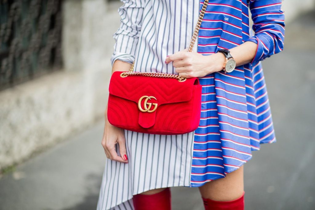 Alexandra Lapp wearing an asymmetric striped blouse by Off-white, red leather over knee boots from Fendi, a red velvet Gucci Marmont handbag with a golden chain and black sunglasses from Celine seen during Milan Fashion Week Fall/Winter 2018/19 on February 24, 2018 in Milan, Italy.