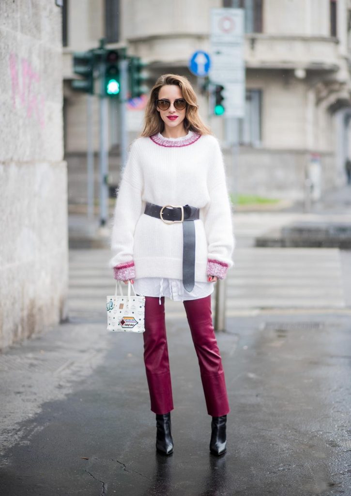 Dorothee Schumacher, MCM, Gianvito Rossi, Maison Mävada Alexandra Lapp wearing flared leather pants in bordeaux by Dorothee Schumacher, an off-white cotton pullover with a bordeaux colored neckline and a long white shirt with a waist line by Dorothee Schumacher, a long black leather belt with a big buckle by Dorothee Schumacher, black leather ankle boots by Gianvito Rossi, cat-eye sunglasses in black with a golden rim by Maison Masada and Anya mini shopper in victory patch from MCM seen during Milan Fashion Week Fall/Winter 2018/19 on February 24, 2018 in Milan, Italy.