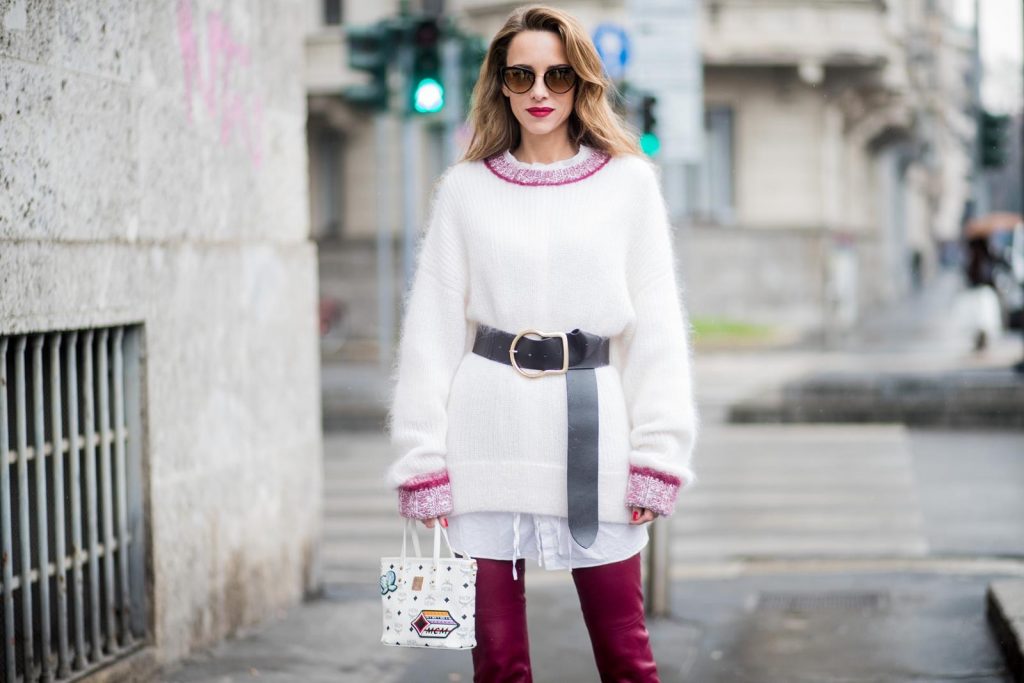 Dorothee Schumacher, MCM, Gianvito Rossi, Maison Mävada Alexandra Lapp wearing flared leather pants in bordeaux by Dorothee Schumacher, an off-white cotton pullover with a bordeaux colored neckline and a long white shirt with a waist line by Dorothee Schumacher, a long black leather belt with a big buckle by Dorothee Schumacher, black leather ankle boots by Gianvito Rossi, cat-eye sunglasses in black with a golden rim by Maison Masada and Anya mini shopper in victory patch from MCM seen during Milan Fashion Week Fall/Winter 2018/19 on February 24, 2018 in Milan, Italy.