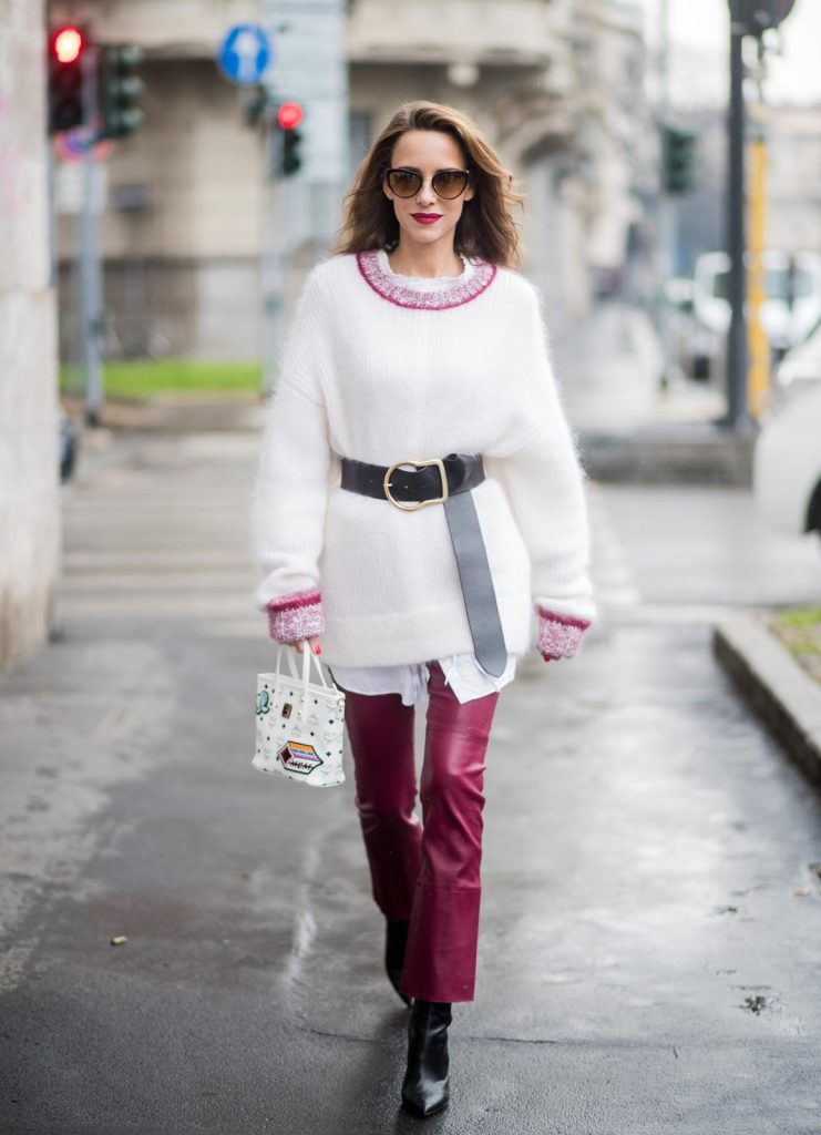 Dorothee Schumacher, MCM, Gianvito Rossi, Maison Mävada Alexandra Lapp wearing flared leather pants in bordeaux by Dorothee Schumacher, an off-white cotton pullover with a bordeaux colored neckline and a long white shirt with a waist line by Dorothee Schumacher, a long black leather belt with a big buckle by Dorothee Schumacher, black leather ankle boots by Gianvito Rossi, cat-eye sunglasses in black with a golden rim by Maison Masada and Anya mini shopper in victory patch from MCM seen during Milan Fashion Week Fall/Winter 2018/19 on February 24, 2018 in Milan, Italy.