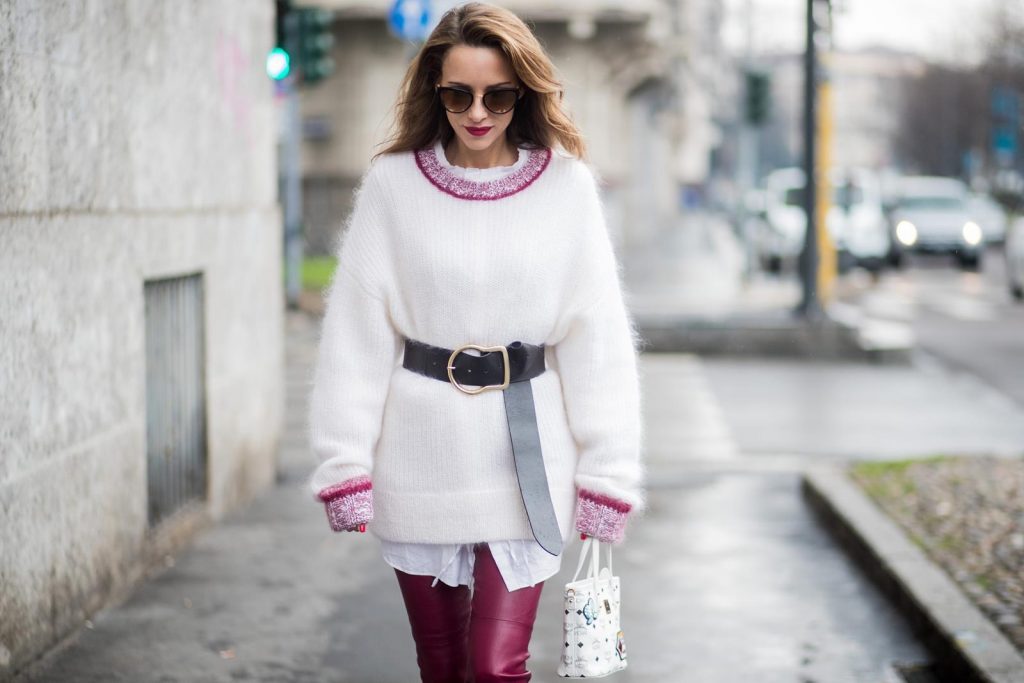 Dorothee Schumacher, MCM, Gianvito Rossi, Maison Mävada Alexandra Lapp wearing flared leather pants in bordeaux by Dorothee Schumacher, an off-white cotton pullover with a bordeaux colored neckline and a long white shirt with a waist line by Dorothee Schumacher, a long black leather belt with a big buckle by Dorothee Schumacher, black leather ankle boots by Gianvito Rossi, cat-eye sunglasses in black with a golden rim by Maison Masada and Anya mini shopper in victory patch from MCM seen during Milan Fashion Week Fall/Winter 2018/19 on February 24, 2018 in Milan, Italy.