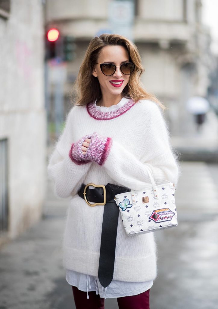Dorothee Schumacher, MCM, Gianvito Rossi, Maison Mävada Alexandra Lapp wearing flared leather pants in bordeaux by Dorothee Schumacher, an off-white cotton pullover with a bordeaux colored neckline and a long white shirt with a waist line by Dorothee Schumacher, a long black leather belt with a big buckle by Dorothee Schumacher, black leather ankle boots by Gianvito Rossi, cat-eye sunglasses in black with a golden rim by Maison Masada and Anya mini shopper in victory patch from MCM seen during Milan Fashion Week Fall/Winter 2018/19 on February 24, 2018 in Milan, Italy.