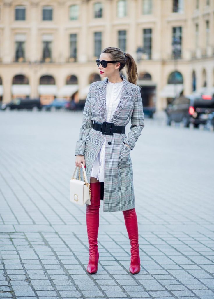 Alexandra Lapp wearing a glencheck coat from Set Fashion, red leather over knee boots from Fendi, a white long shirt from Dorothee Schumacher, a black waist belt from Dolce & Gabbana, a red short bomber jacket with a dark red fur collar from Yves Salomon, off white Madame Viv bag from Roger Vivier and black sunglasses from Celine is seen on February 28, 2018 in Paris, France.