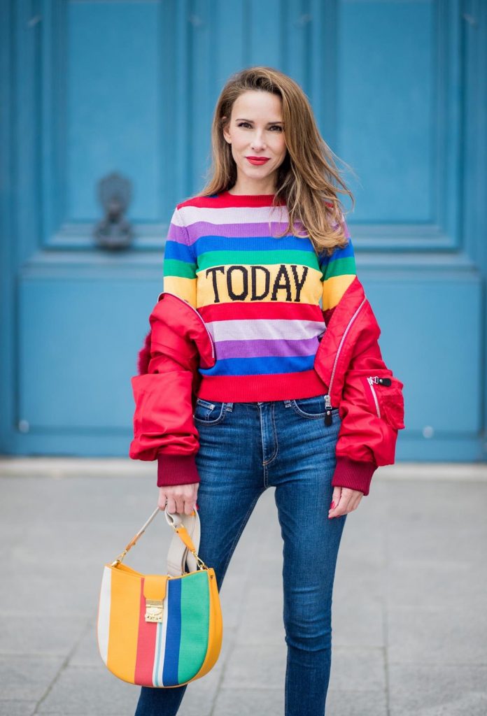 Alberta Ferretti, Yves Salomon, Adriano Goldschmied, MCM, Ray Ban, Gianvito Rossi PARIS, FRANCE - FEBRUARY 28: Alexandra Lapp wearing Pullover Alberta Ferretti with today print, AG Jeans denim, Bag MCM Patricia Hobo bag in striped Canvas, Aviator Sunglasses in green from Ray Ban, Heels Gianvito Rossi in patent red, jacket Yves Salomon is seen on February 28, 2018 in Paris, France.