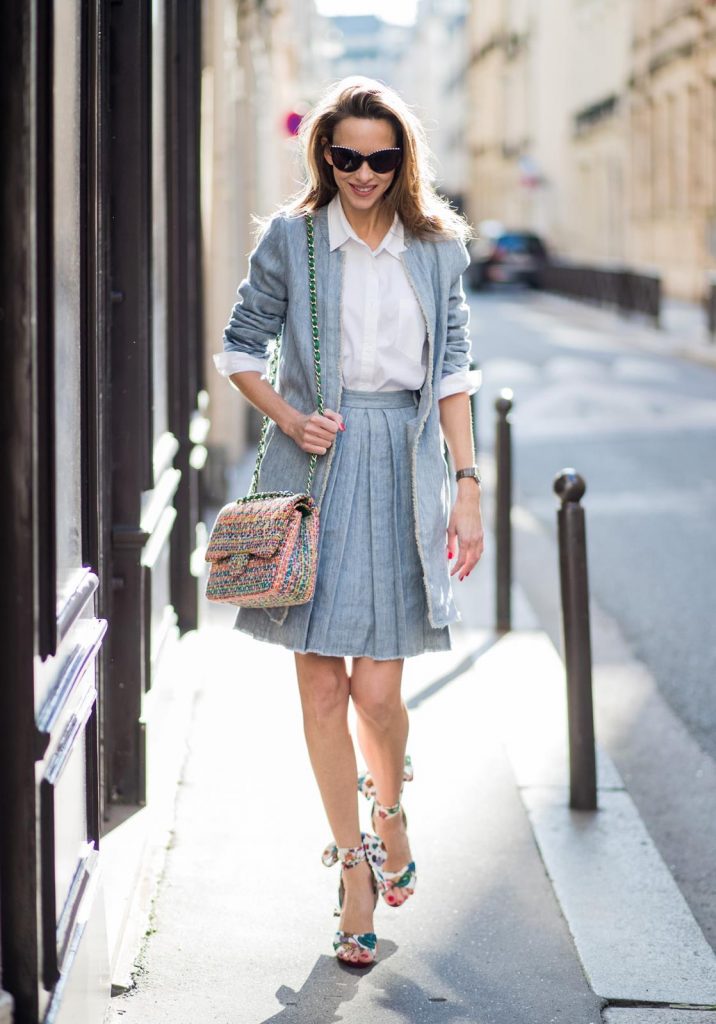 Steffen Schraut, Christian Louboutin, Chanel, IWC Alexandra Lapp in Linen Chic wearing a linen open front blazer with a fringed hem line in a denim optic and a high waist linen pleated skirt in denim optic and a fringed hem line by Steffen Schraut, a white blouse from Steffen Schraut, a 2.55 Chanel bag in multicolor, high heel sandals with a long satin bow with fruit motifs by Christian Louboutin and brown Chanel sunglasses with pearls seen on March 2, 2018 in Paris, France.