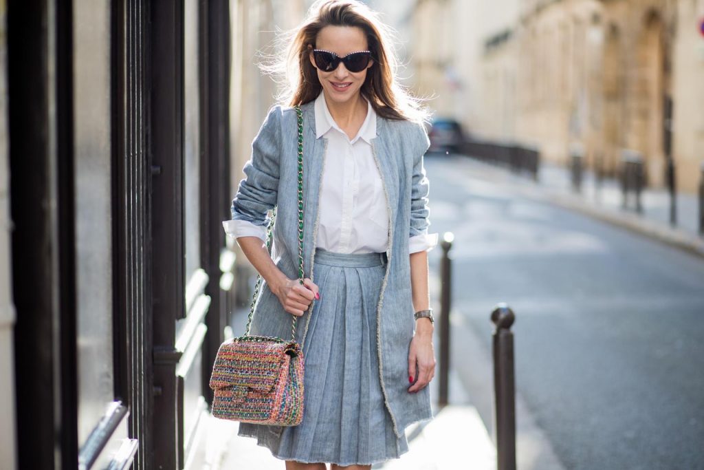 Steffen Schraut, Christian Louboutin, Chanel, IWC Alexandra Lapp in Linen Chic wearing a linen open front blazer with a fringed hem line in a denim optic and a high waist linen pleated skirt in denim optic and a fringed hem line by Steffen Schraut, a white blouse from Steffen Schraut, a 2.55 Chanel bag in multicolor, high heel sandals with a long satin bow with fruit motifs by Christian Louboutin and brown Chanel sunglasses with pearls seen on March 2, 2018 in Paris, France.