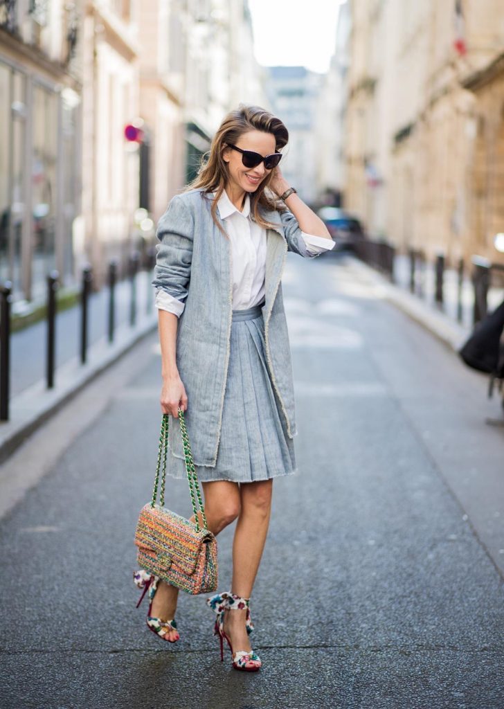Steffen Schraut, Christian Louboutin, Chanel, IWC Alexandra Lapp in Linen Chic wearing a linen open front blazer with a fringed hem line in a denim optic and a high waist linen pleated skirt in denim optic and a fringed hem line by Steffen Schraut, a white blouse from Steffen Schraut, a 2.55 Chanel bag in multicolor, high heel sandals with a long satin bow with fruit motifs by Christian Louboutin and brown Chanel sunglasses with pearls seen on March 2, 2018 in Paris, France.