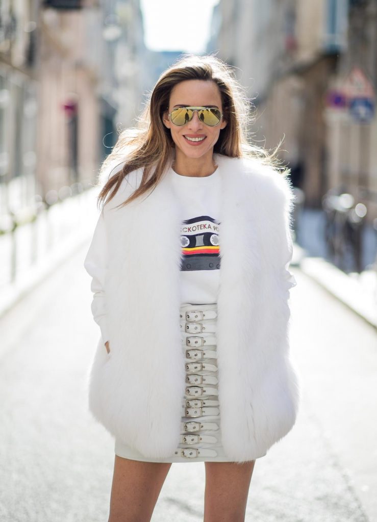 Alexandra Lapp in Think White: she is seen wearing a white leather miniskirt from Manokhi, Selfmade Sweater from Wodka Ogurez, Yves Salomon fur veste in white, Aldo heels with red lips, vintage Ray-ban in yellow and a boy bag from Chanel in gold during Paris Fashion Week Womenswear Fall/Winter 2018/2019 on March 5, 2018 in Paris, France.