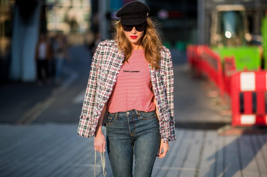 Alexandra Lapp wearing a striped shirt look with Saint Laurent Logo jersey T-Shirt in red-white, a white/blue/red Tweed Jacket by Balmain, dark blue Levis Super Skinny jeans, Prada flame shoes, the Chanel Perfume Bottle Bag in clear plexiglass, vintage Chanel Bakerboy cap and black Celine sunglasses on May 3, 2018 in Duesseldorf, Germany.