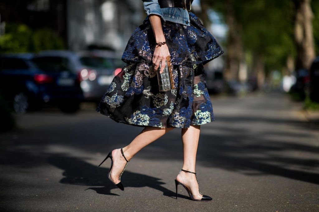Alexandra Lapp wearing a Marchesa Notte dress with tiered corded lace and brocade in a mix of black, midnight-blue and gold by Marchesa Notte, blue trucker denim jacket by Levis, a gold buckle belt by Dorothee Schumacher, black Nosy t-bar Christian Louboutin sandals with a studded strap, handmade bracelet with rosegold fleur de lis lock by Coerlys and a vintage Chanel clutch in gold on May 3, 2018 in Duesseldorf, Germany.