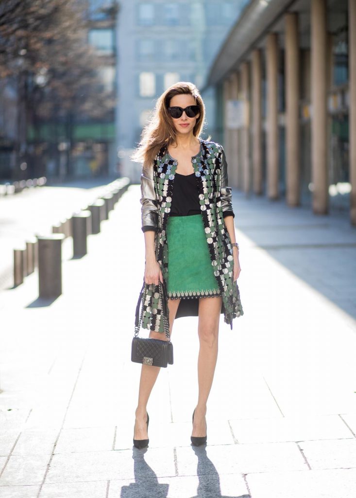 Yves Salomon, Jadicted, Chanel, Christian Louboutin, Celine Alexandra Lapp wearing a silver coat from Yves Salomon with silver, green and black round leather parts with studs on the front, a short green suede leather skirt with blue and light grey pieces around the bottom line with studs by Yves Salomon, a black satin top from Jadicted, a black Chanel boy bag, black suede pumps by Christian Louboutin and black Celine sunglasses during Paris Fashion Week Womenswear Fall/Winter 2018/2019 on March 3, 2018 in Paris, France.