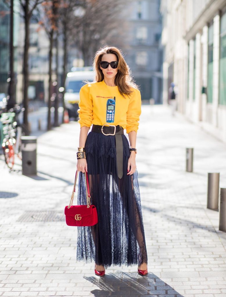 Wodka Ogurez, Self-Portrait, Dorothee Schumacher, Gucci, Gianvito Rossi, Chanel, Céline Alexandra Lapp in handmade print Wodka Ogurez sweater in yellow with handmade Nokia phone print, long dark blue Self-Portrait lace dress underneath, Dorothee Schumacher waist belt with big golden buckle, red patent Gianvito Rossi pumps, Chanel bracelet with golden CC sign, golden vintage Chanel bracelet, red velvet Gucci Marmont bag and Celine Audrey sunglasses during Paris Fashion Week Womenswear Fall/Winter 2018/2019 on March 3, 2018 in Paris, France.