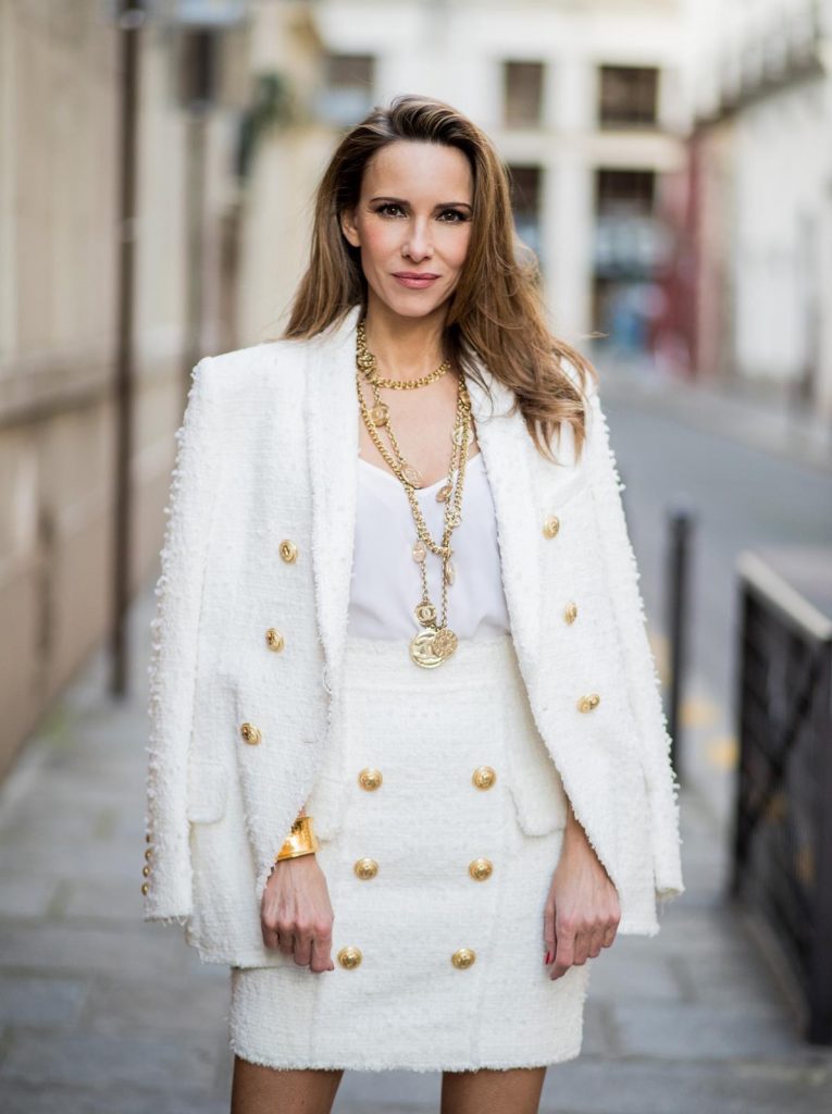 Alexandra Lapp in a full Balmain costume - a white tweed blazer with golden buttons and a matching tweed mini skirt with golden buttons both Balmain, a white silk top from Jadicted, heels from Christian Louboutin and Vintage necklaces from Chanel during Paris Fashion Week Womenswear Fall/Winter 2018/2019 on March 4, 2018 in Paris, France.
