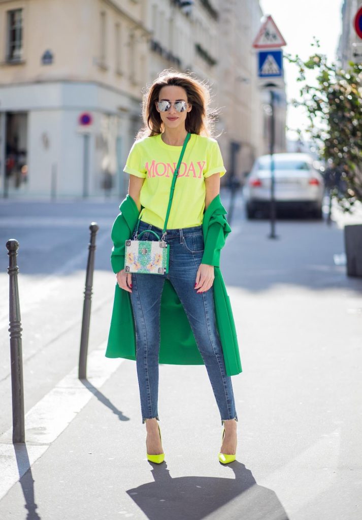 Alexandra Lapp in Mondays Statement Shirt Look wearing a yellow neon t-shirt with pink letters writing Monday by Alberta Ferretti, a blue pair of AG Jeans, a green coat from Stella McCartney, yellow neon pumps by Christian Louboutin, the Berlin cross body bag with crystal flowers from MCM and sunglasses by Le Specs during Paris Fashion Week Womenswear Fall/Winter 2018/2019 on March 5, 2018 in Paris, France.