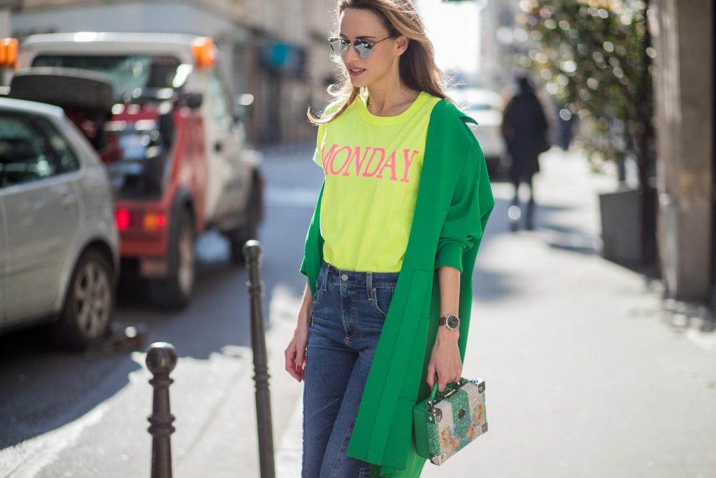 Alexandra Lapp in Mondays Statement Shirt Look wearing a yellow neon t-shirt with pink letters writing Monday by Alberta Ferretti, a blue pair of AG Jeans, a green coat from Stella McCartney, yellow neon pumps by Christian Louboutin, the Berlin cross body bag with crystal flowers from MCM and sunglasses by Le Specs during Paris Fashion Week Womenswear Fall/Winter 2018/2019 on March 5, 2018 in Paris, France.